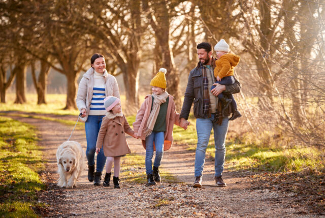 a family walking with a dog outdoors in the fall